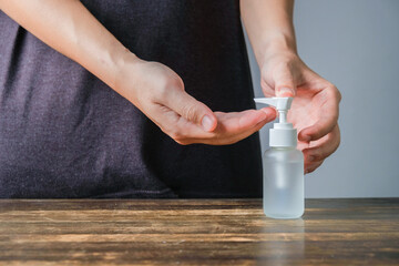 Close up shot of male hand dispensing alcohol based sanitizer on hands from small portable bottle to kill bacteria and virus.