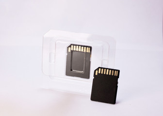 Two black memory cards on white background, one in case