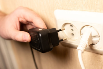 man plugs a charger into a wall outlet
