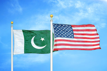 Pakistan and United States two flags on flagpoles and blue cloudy sky