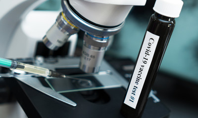 Coronavirus vaccine standing near the microscope in laboratory.