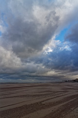 Dunkirk Beach and Sea Front with People walking along it under a dramatic Sky on a windy November Morning.