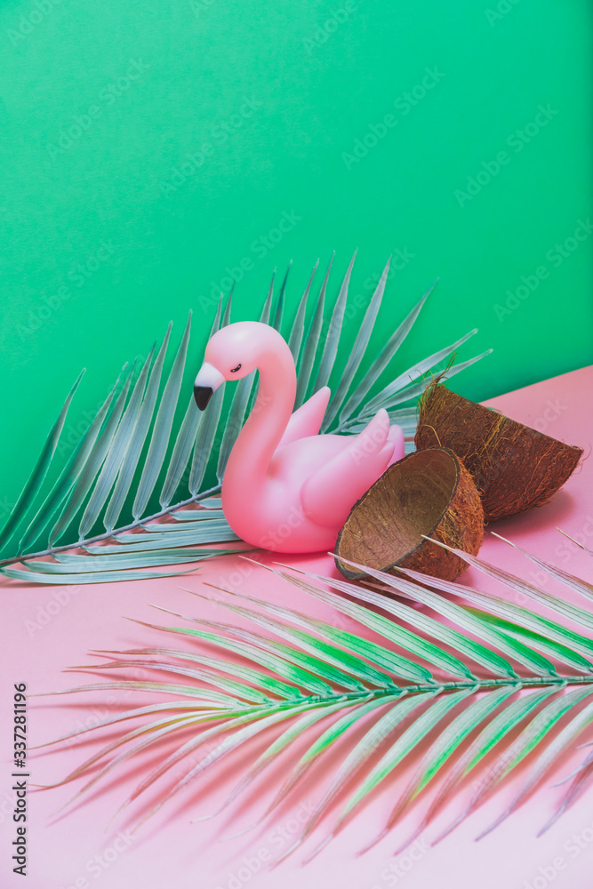 Wall mural plastic flamingo, coconut shells and tropical palm leaves on green and pink background. hot summer v