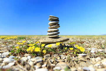 Rock balancing, stone stacks on the beach, blue sky in background - Powered by Adobe