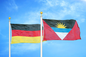 Germany and Antigua and Barbuda two flags on flagpoles and blue cloudy sky