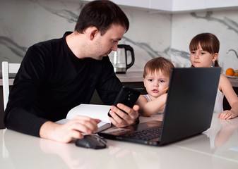 Young children distract their father from work at home. A man works at home with a laptop. 