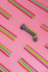 Rainbow chewable candy gums on pink background. Flat lay, top view. Geometric pattern.