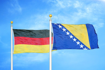 Germany and Bosnia and Herzegovina two flags on flagpoles and blue cloudy sky