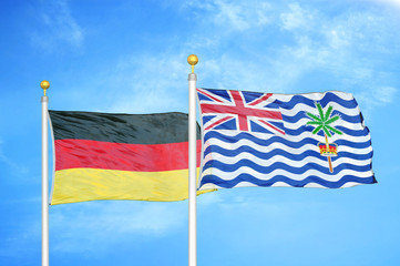Germany and British Indian Territory two flags on flagpoles and blue cloudy sky