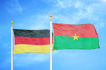 Germany and Burkina Faso two flags on flagpoles and blue cloudy sky