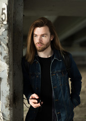 Portrait of a young handsome man. Long brown hair, beard, blue eyes, 30 years old.