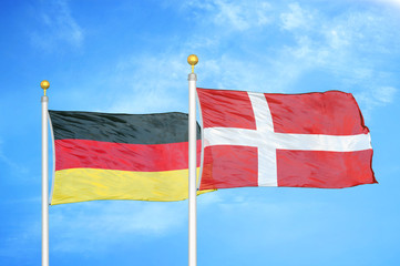 Germany and Denmark two flags on flagpoles and blue cloudy sky