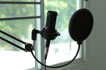 Condenser studio microphone with shock mount and windscreen in a music studio. Musical Concept