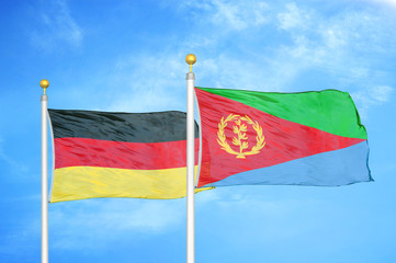 Germany and Eritrea two flags on flagpoles and blue cloudy sky