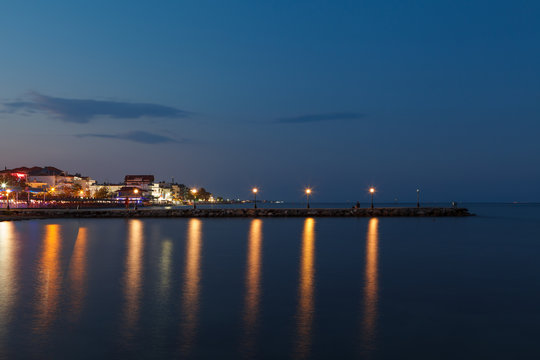 Paralia seaside promenade with lanterns, buildings and lighthouses in the port