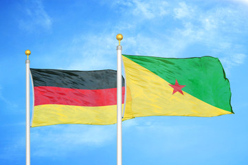 Germany and French Guiana two flags on flagpoles and blue cloudy sky