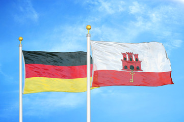 Germany and Gibraltar two flags on flagpoles and blue cloudy sky