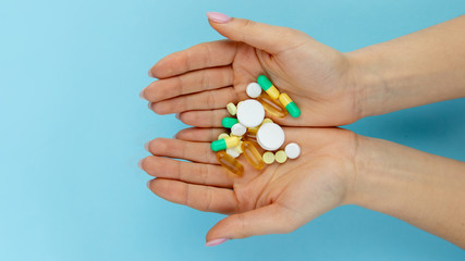 Woman's holding cupped hand full of pills, view from above.