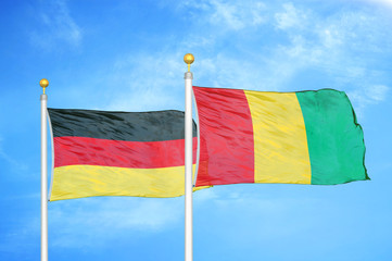 Germany and Guinea two flags on flagpoles and blue cloudy sky