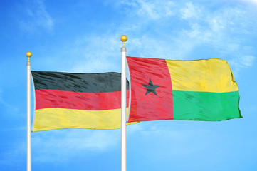 Germany and Guinea-Bissau two flags on flagpoles and blue cloudy sky