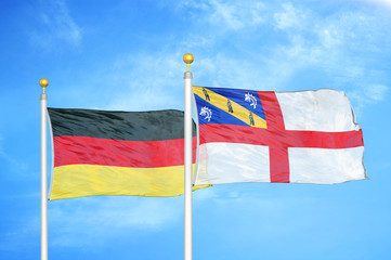 Germany and Herm two flags on flagpoles and blue cloudy sky