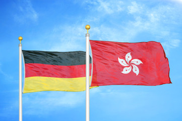Germany and Hong Kong two flags on flagpoles and blue cloudy sky