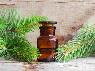 Pharmacy bottle with essential pine oil (extract, tincture, infusion). Old wooden background. Aromatherapy, spa and herbal medicine concept. Copy space.
