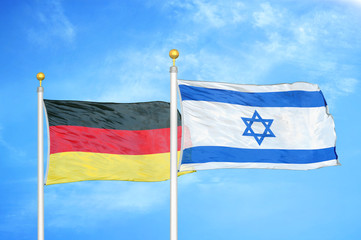 Germany and Israel two flags on flagpoles and blue cloudy sky