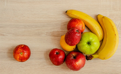 apples, bananas, lemon and oranges on a wooden table 