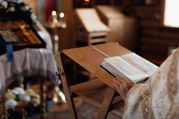 Naklejka na ściany i meble Orthodox church, a priest in a white cassock recites a prayer, a prayer book, a golden church interior, candles, icons, an altar