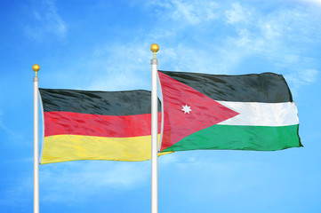 Germany and Jordan two flags on flagpoles and blue cloudy sky