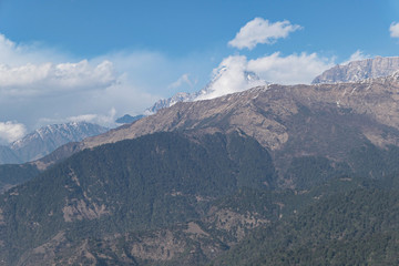 High mountains peak. White clouds. Green forest.