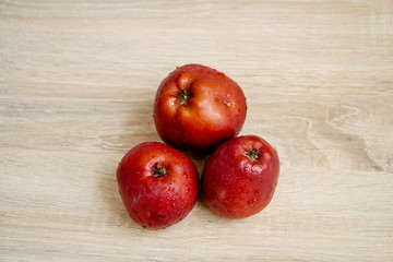 Fototapeta na wymiar three juicy red apples on a wooden table