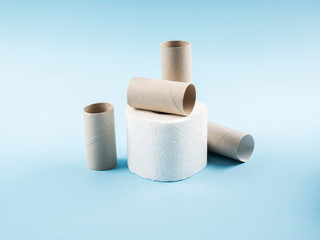 White toilet paper and empty rolls on blue abstract background. Personal hygiene supplies for restroom. Panic concept during coronavirus pandemic.