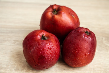 three juicy red apples on a wooden table