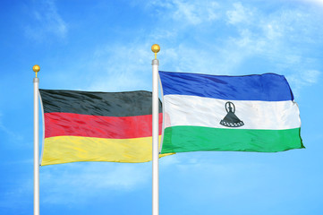 Germany and Lesotho two flags on flagpoles and blue cloudy sky
