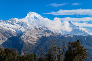 High mountains peak. White clouds. Green forest.