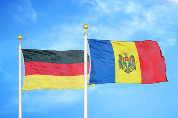 Germany and Moldova two flags on flagpoles and blue cloudy sky