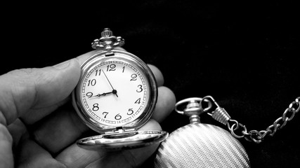 Two antique old pocket watches one being held in hand. Black and white