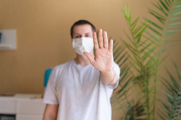 face of a man in a mask from the coronavirus virus. the hand is extended forward, a stop gesture . covid-19 virus pandemic