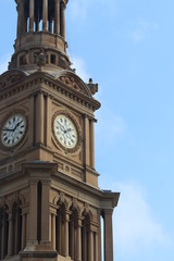 Fototapeta na wymiar Large clock face showing two o'clock on The Sydney Town Hall building. Blue sky background. Australia
