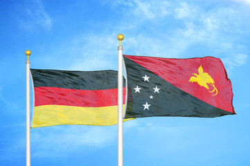 Germany and Papua New Guinea two flags on flagpoles and blue cloudy sky