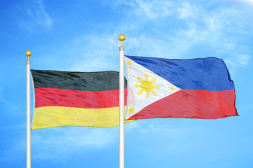 Germany and Philippines two flags on flagpoles and blue cloudy sky
