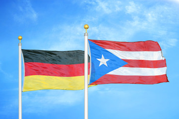 Germany and Puerto Rico two flags on flagpoles and blue cloudy sky