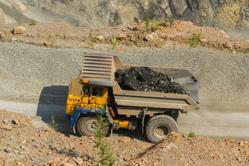 A daytime general view of the iron ore quarry. In sunny weather. Apparently, special equipment is used. Larger trucks transport ore. Tipper trucks transport iron ore.