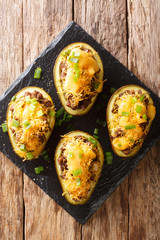 baked avocado stuffed with ground beef, onions and cheddar cheese close-up on a slate board. vertical top view