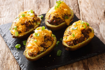 Healthy baked avocado food with ground beef, green onions, garlic and cheddar cheese close-up on a slate board on the table. horizontal