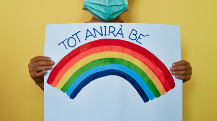 A child with medical mask and rainbow message in Catalan Spanish