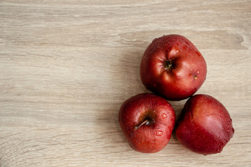 three juicy red apples on a wooden table
