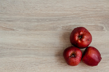 three juicy red apples on a wooden table